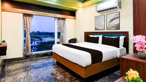 Una habitación de hotel con una cama grande, un escritorio, un equipo de aire acondicionado y vistas al exterior.