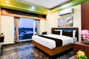 Ein Hotelzimmer mit einem großen Bett, einem Schreibtisch, einer Klimaanlage und Blick ins Freie.