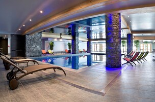 Une piscine intérieure avec des chaises longues et un pilier en pierre.