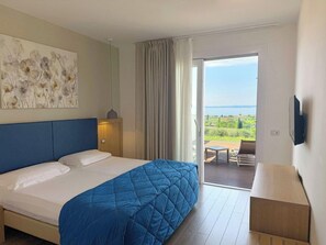 Ett hotellrum med en stor säng, utsikt över omgivningarna och en tv på väggen.