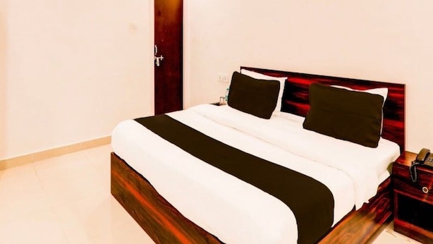 Ein Hotelzimmer mit einem Bett, einem hölzernen Kopfteil, einem Nachttisch und einer Tür.