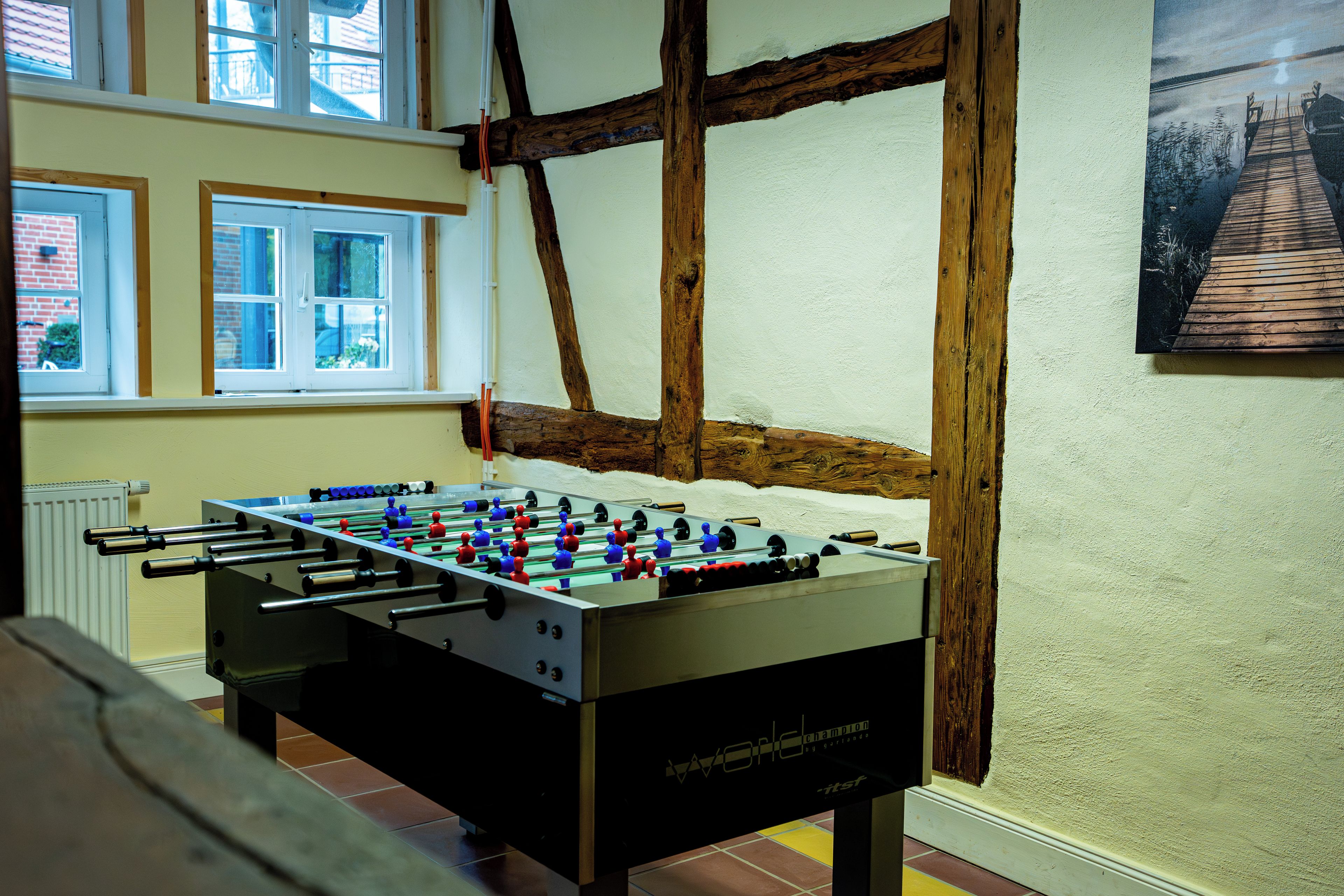 A foosball table in a room with exposed wooden beams and a window.