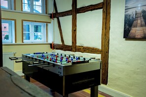 Ein Tischkicker in einem Raum mit freiliegenden Holzbalken und einem Fenster.