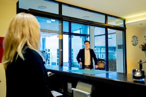 En reception med et stort vindue, et ur på væggen og en stol i forgrunden.