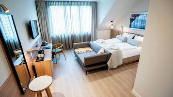 A modern hotel room with a bed, a desk, a chair, and a large window with curtains.