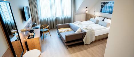 A modern hotel room with a bed, a desk, a chair, and a large window with curtains.