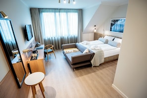 Ein modernes Hotelzimmer mit Bett, Schreibtisch, Stuhl und einem großen Fenster mit Vorhängen.