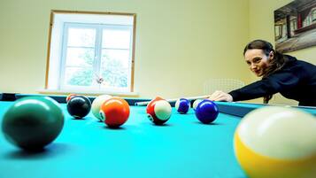 A pool table with balls in a room with a window and a painting on the wall.