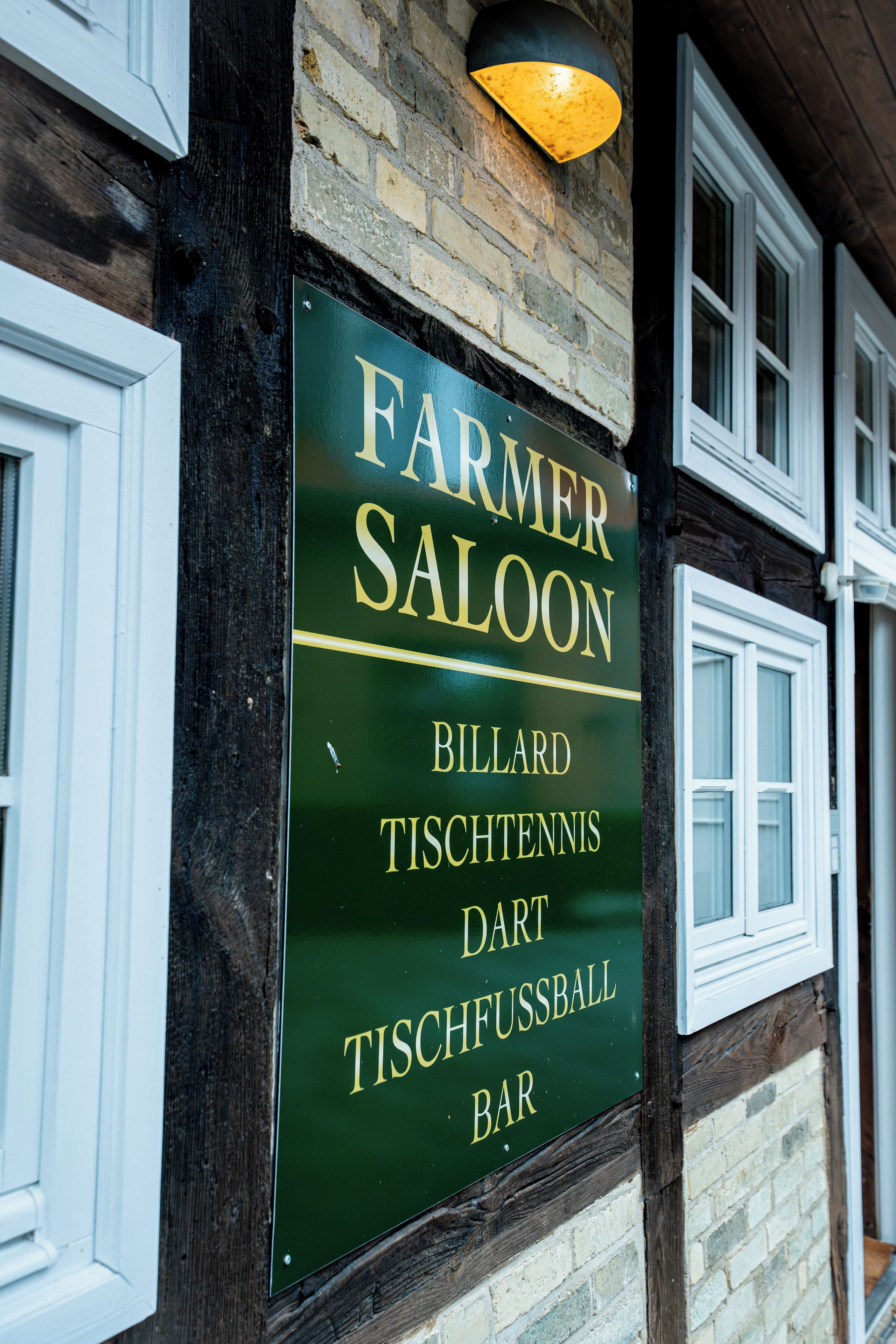A sign for a bar named 'Farmer Saloon' with amenities listed as billiards, table tennis, darts, and table football.