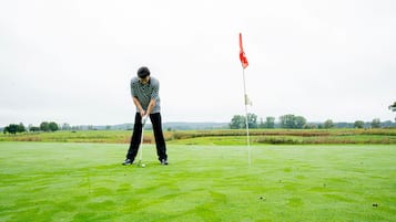 Eine Person auf einem Golfplatz, im Hintergrund ein Fahnenstange.