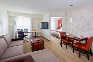 A hotel room with a sofa, a desk with a computer, a television, a dining table with chairs, and a bed. - Residence Inn by Marriott Madison East (Madison)