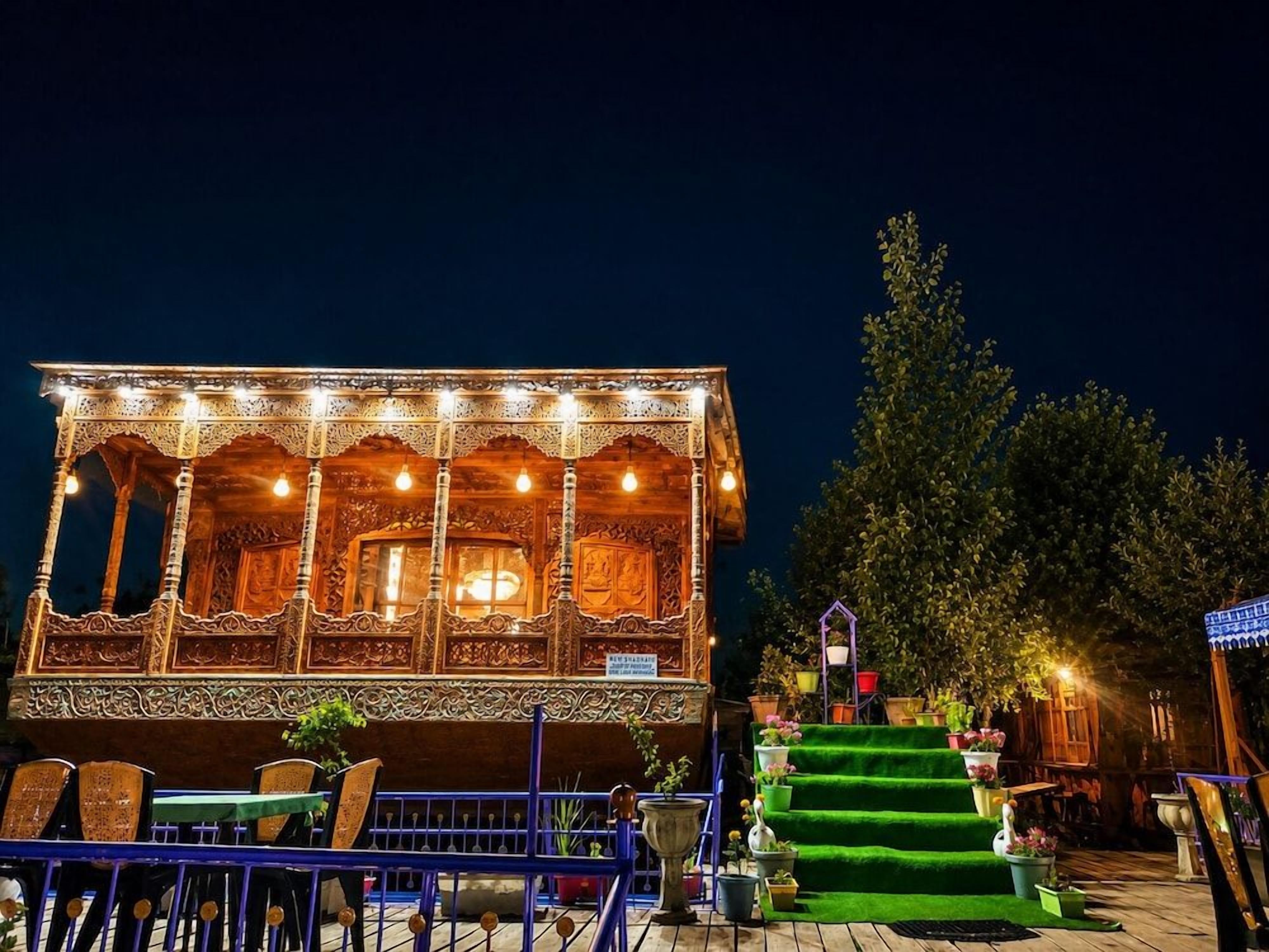 A building with intricate architectural details, a staircase leading to the entrance, and outdoor seating area with tables and chairs.