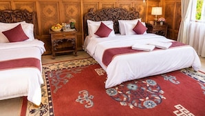 A hotel room with two beds, a wooden headboard, a red patterned rug, and a wall with intricate paneling. - De - Laila Group Of House Boats (Srinagar)