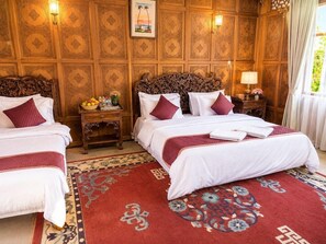 A hotel room with two beds, a wooden headboard, a red patterned rug, and a wall with intricate paneling. - De - Laila Group Of House Boats (Srinagar)