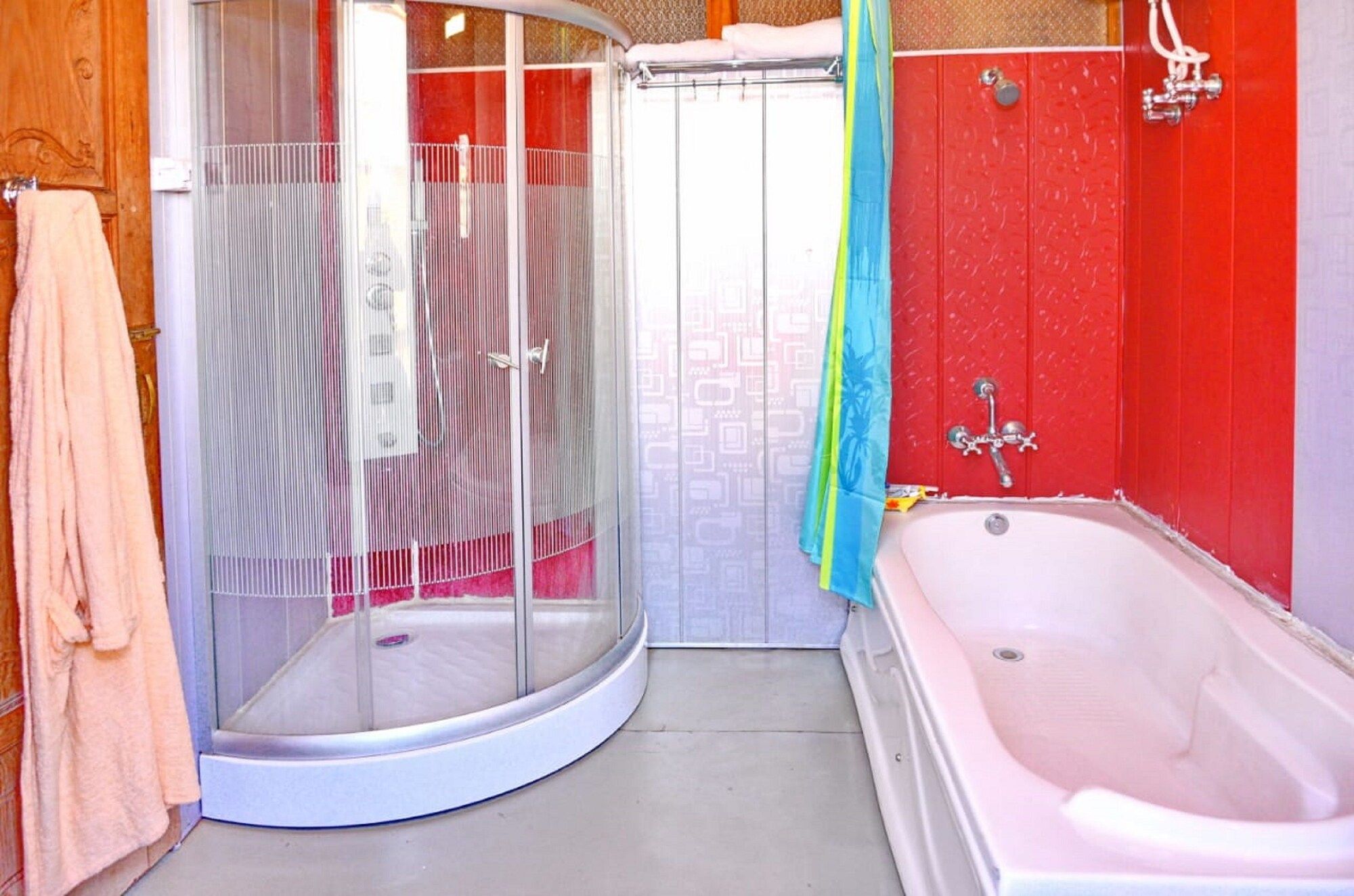 A bathroom with a shower enclosure, a bathtub, and a towel rack.