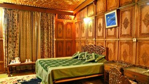 A room with a bed, wooden paneling, a nightstand, and a framed picture on the wall. - De - Laila Group Of House Boats (Srinagar)