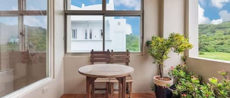 A room with a window, a table, and chairs, and a potted plant.