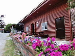 A wooden cabin with a picnic table and a sign that reads 'Come Inn.' - Come Inn (Hengchun)