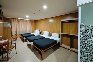 Een hotelkamer met twee bedden, een bureau met stoel, een kleine kitchenette en een badkamer met douche.