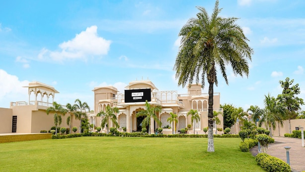 A hotel with a signboard, palm trees, and a well-maintained lawn. - Family Rooms With Twin King bed Amar Resorrt (Motihari)