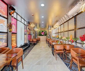 A restaurant interior with a central counter, multiple tables, chairs, and decorative wall elements.