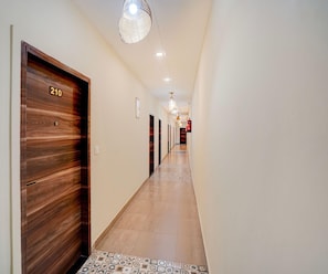A hotel hallway with wooden doors, numbered 210, and a patterned floor.