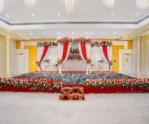A stage with red and white drapes, floral arrangements, and a patterned carpet.
