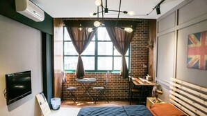 A bedroom with a bed, a desk, a chair, a TV, and a window with curtains. - Loft.wo Design Inn (Tainan)