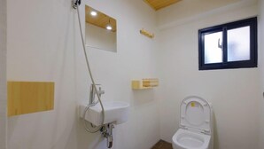 A small bathroom with a toilet, a sink, a shower, and a window. - Loft.wo Design Inn (Tainan)