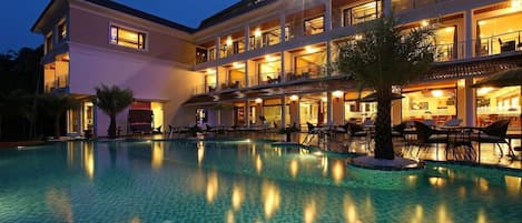 A hotel with a swimming pool, multiple balconies, and outdoor seating areas.