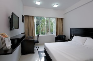 A hotel room with a bed, desk, chair, and a television. - Keys Hotel (Thiruvananthapuram)