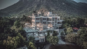 A multi-story building with a glass-enclosed terrace and multiple birdcages. - The Royal Retreat (Udaipur)