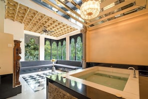 A spa area with a large bathtub, a checkered floor, and a ceiling with a wooden pattern. - The Royal Retreat (Udaipur)