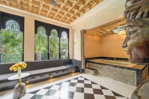 Un baño moderno con una bañera grande, piso de mármol y vistas a la vegetación exterior.