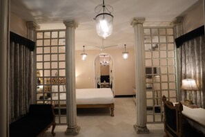 A room with a bed, a desk, and a chair, with columns and a chandelier. - The Royal Retreat (Udaipur)