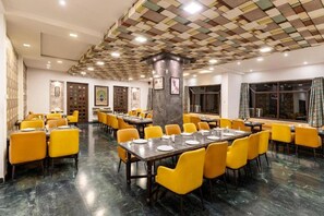 Un comedor con varias mesas y sillas, techo con diseño y obras de arte enmarcadas en las paredes.