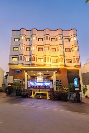 Un hotel con fachada moderna, varios balcones y una entrada destacada con un cartel.