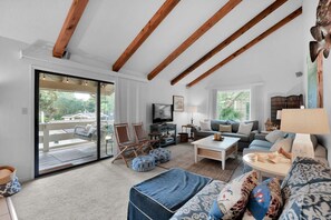 A spacious living room with a large sliding glass door leading to an outdoor deck, a sofa set, a coffee table, and a television. - 3 Bedroom- Seascape Golf and Beach Resort (Miramar Beach)
