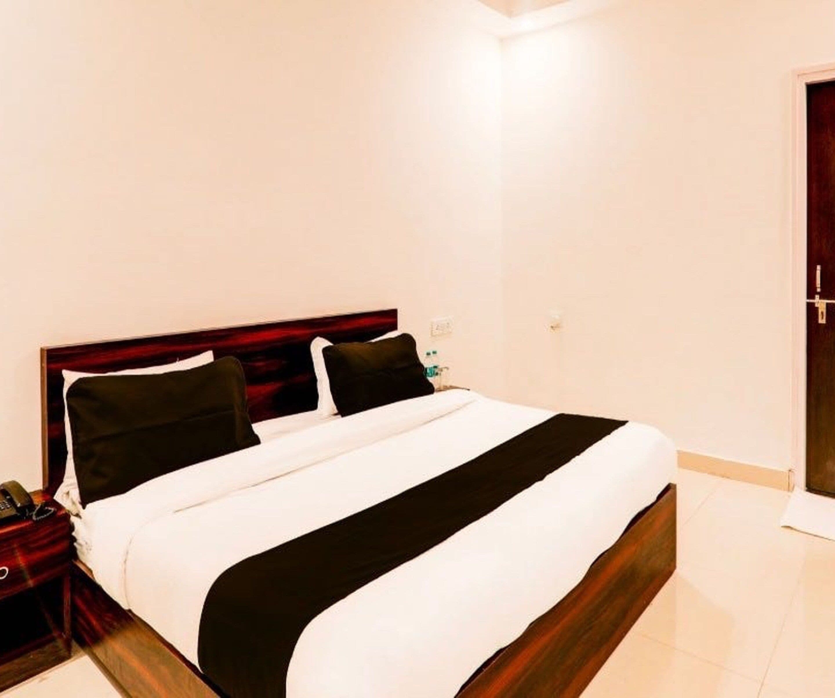A hotel room with a bed, a nightstand, and a door.