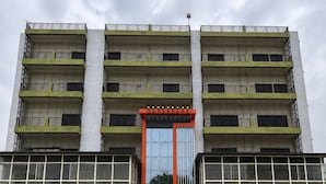 Un immeuble à plusieurs étages doté d’une entrée centrale, de balcons et d’une façade en verre réfléchissant.