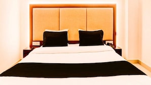 Une chambre d’hôtel avec un grand lit, deux tables de chevet et une tête de lit dotée d’un panneau lumineux.