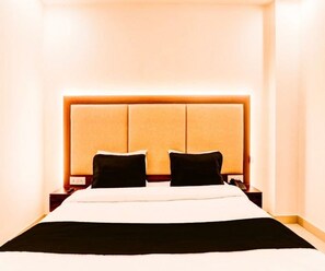 Une chambre d’hôtel avec un grand lit, deux tables de chevet et une tête de lit dotée d’un panneau lumineux.
