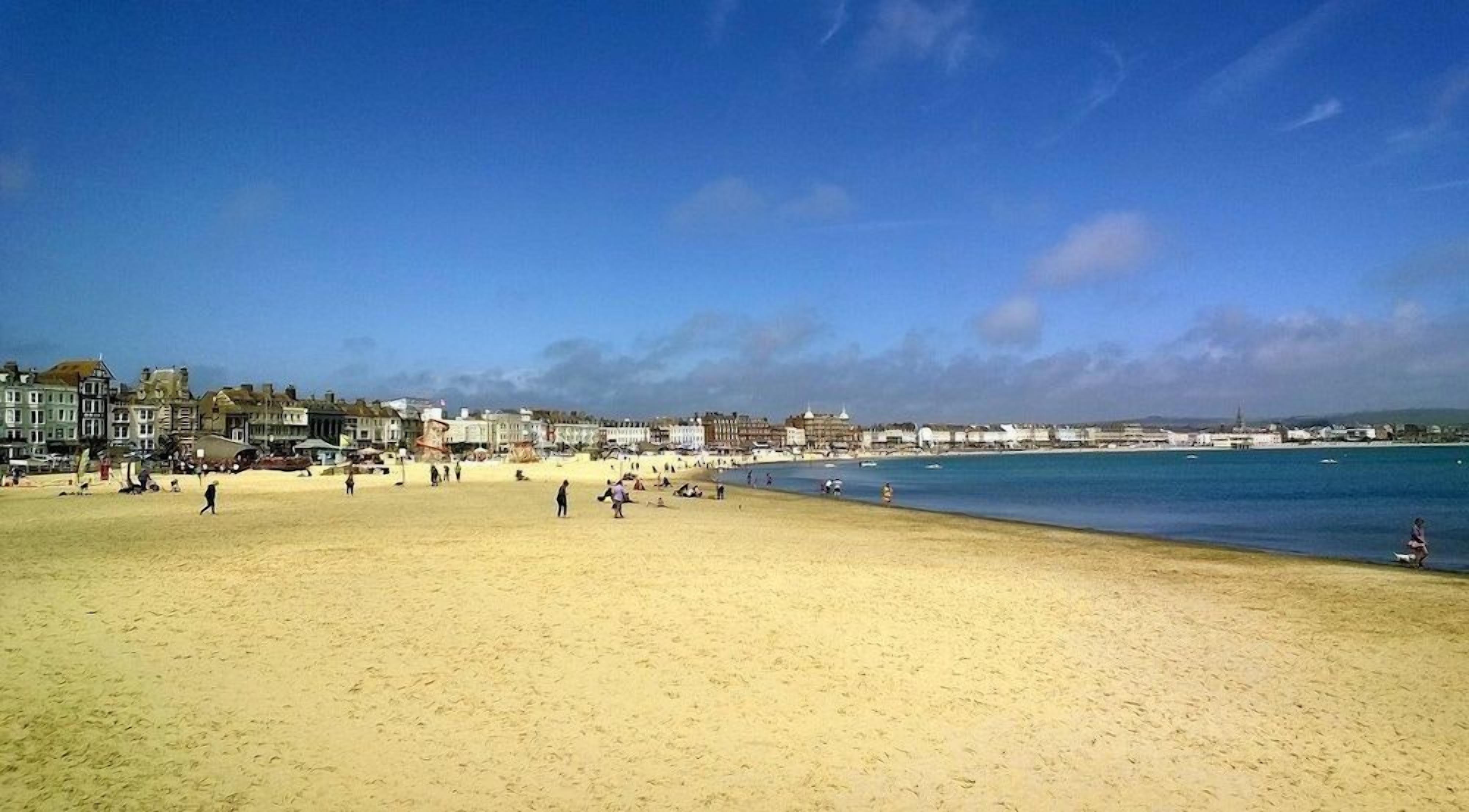 A beach with buildings in the background and a clear sky.