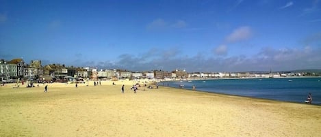 Une plage avec des bâtiments en arrière-plan et un ciel dégagé.