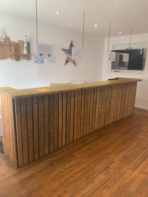 Un mostrador de recepción con detalles de madera, una lámpara colgante y un letrero en la pared.