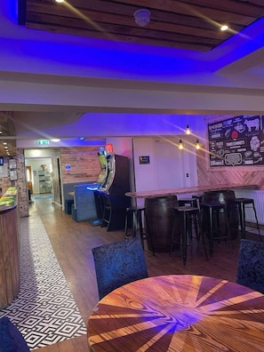 Zona de bar con mostrador, taburetes y un letrero de neón.