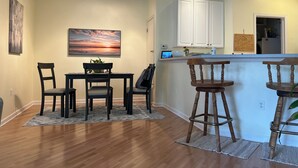 Een moderne keuken met witte kasten, een bar en een eettafel met stoelen.