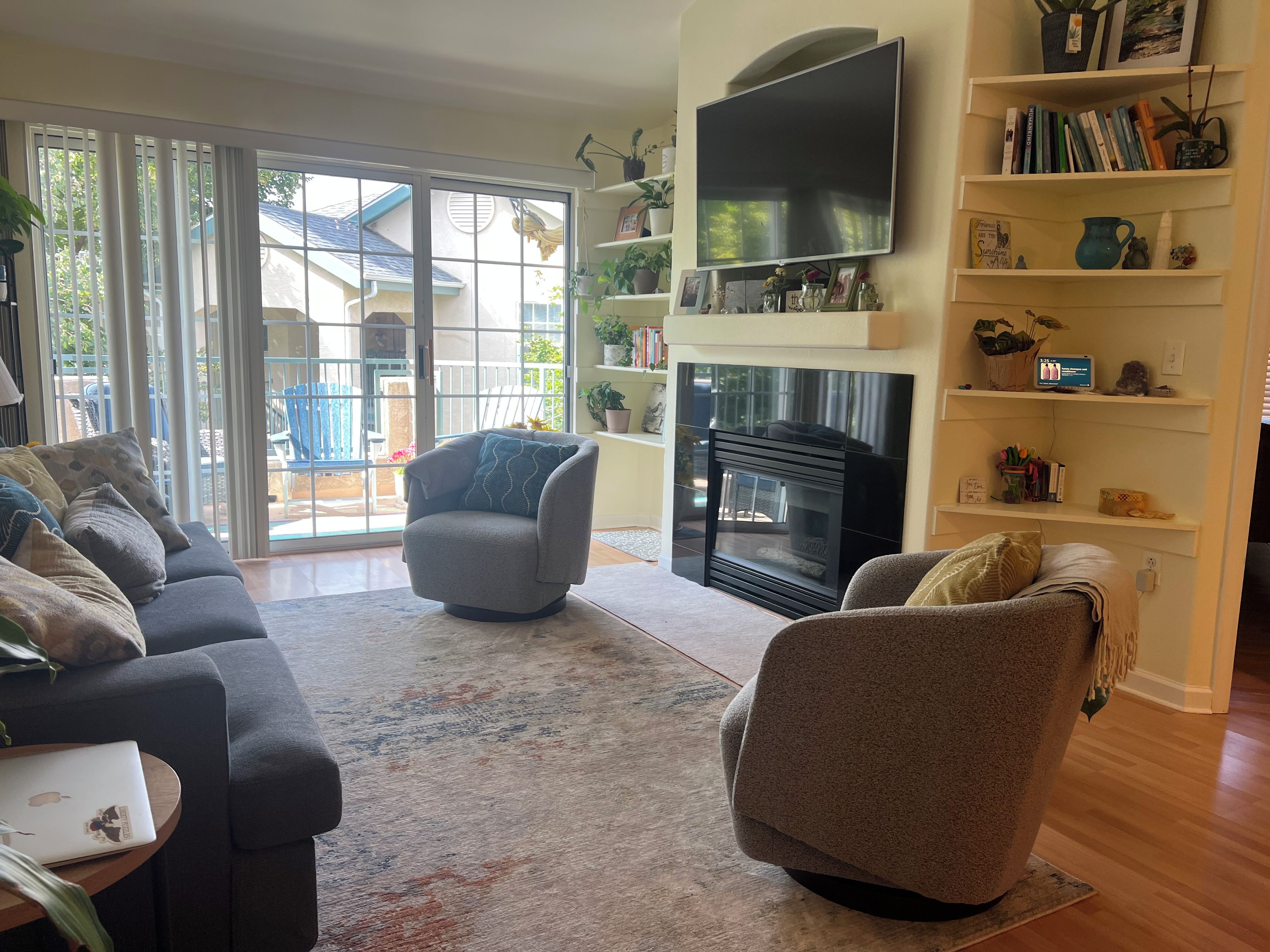Una sala de estar con chimenea, un sofá, una silla y una estantería.