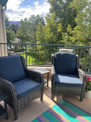 Un balcon agrémenté de meubles en osier et d’un tapis aux couleurs vives.