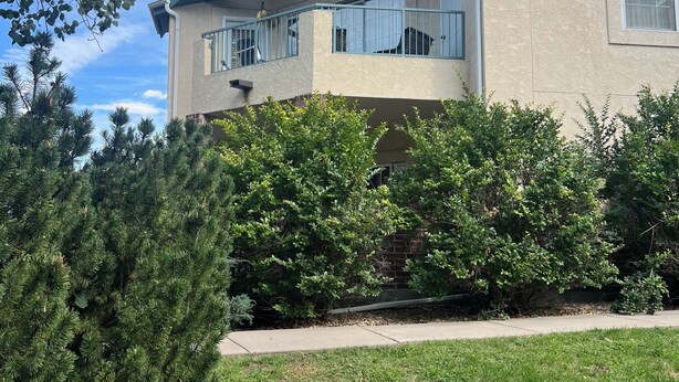 Een tweelaags huis met een overdekt balkon, een bakstenen muur en een gazon.